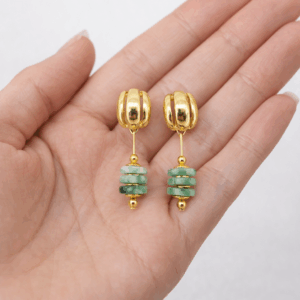 brincos de agata three banhado a ouro 18k na mão da modelo.