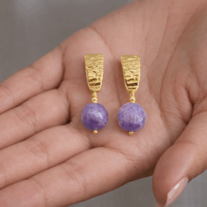 brincos de ametista banhados a ouro 18 k. na mão da modelo