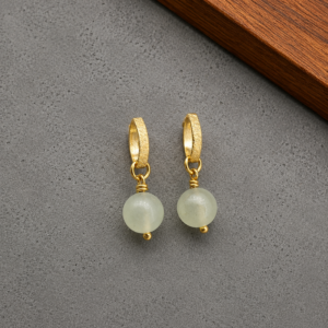 BRINCOS de jade banhados a ouro 18k. Fundo de cimento queimado.