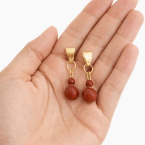 brincos jaspe vermelho banhados a ouro 18k. na palma da mão da modelo.