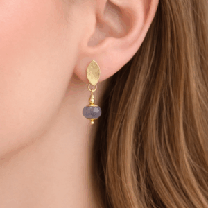 brincos de safira base escovada, banhados a ouro 18k.no lobulo da modelo.