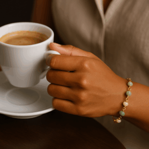 Mulher usando pulseira de amazonita com elo português banhada a ouro enquanto segura uma xícara de café, destacando o brilho dourado e as pedras naturais