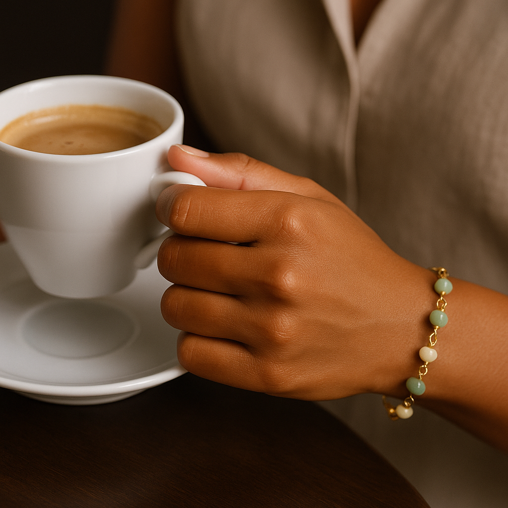 Mulher usando pulseira de amazonita com elo português banhada a ouro enquanto segura uma xícara de café, destacando o brilho dourado e as pedras naturais Mulher usando pulseira de amazonita com elo português banhada a ouro enquanto segura uma xícara de café, destacando o brilho dourado e as pedras naturais