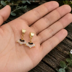 brincos de onix e pedra da lua banhados a ouro 18 k, na palma da mao da modelo.