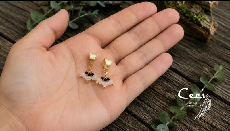 brincos de onix e pedra da lua banhados a ouro 18 k, na palma da mao da modelo. brincos de onix e pedra da lua banhados a ouro 18 k, na palma da mao da modelo.