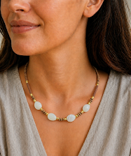 colar de agata cinza, madeira, entremeios e fechos com banho de ouro 18k. no colo da modelo.