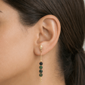 brincos de turquesa africanabanhados a ouro 18k no lobulo da modelo