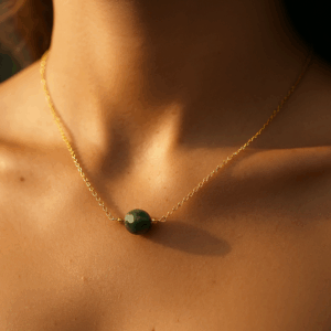 Colar elo português com ágata indiana de 8 mm folheado a ouro 18k no colo de uma mulher, luz de fim de tarde