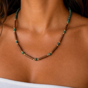 colar de turquesa africana fosca, cerâmica feita a mão, entremeios e fechos banhados a ouro 18 k, no colo da modelo.