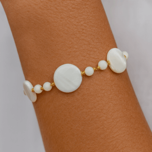 pulseira artesanal de madrepérola com esferas e bolachinhas intercaladas por entremeios banhados a ouro 18k no pulso feminino – biojoia exclusiva Ceci Joias da Amazônia.