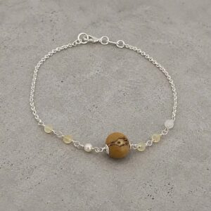 Pulseira de açai e madreperola sobre o cimento queimado. Feito pela Ceci joias.