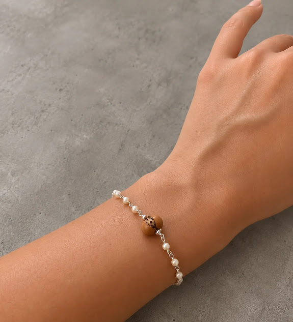 pulseira de açai e madreperolas de 3 mm, corrente elo portugues banhada a prata no punho da modelo.