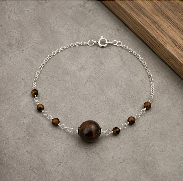 pulseira de açai e olho de tigre , corrente elo pórtugues banhada a prata sobre o cimento queimado.