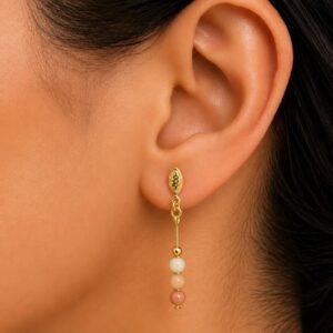 Mulher usando brinco pendente de aventurina pêssego e ouro 18k, demonstrando o tamanho e a leveza de 3,5 cm Imagem 3 (fundo branco):