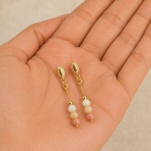 Brincos pendentes de aventurina pêssego com ouro 18k, exibidos na palma da mão, mostrando as esferas polidas de 4mm e o acabamento banhado em ouro